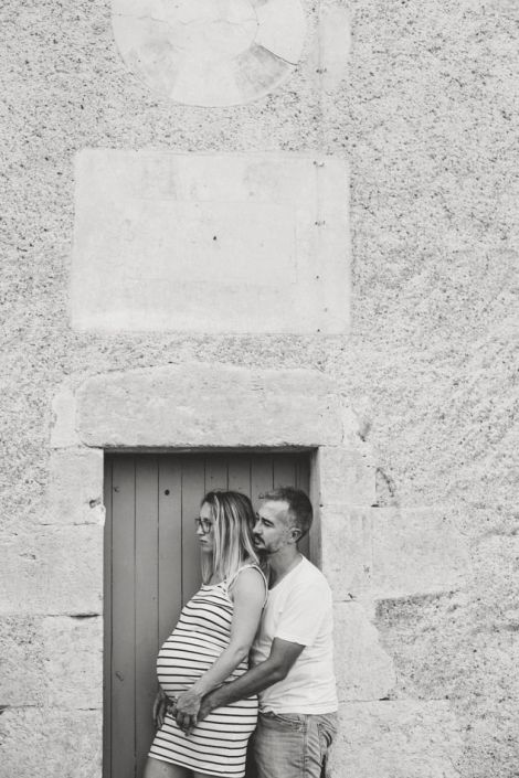 Tendrement enlacés et posés contre une porte durant une seance photo de grossesse