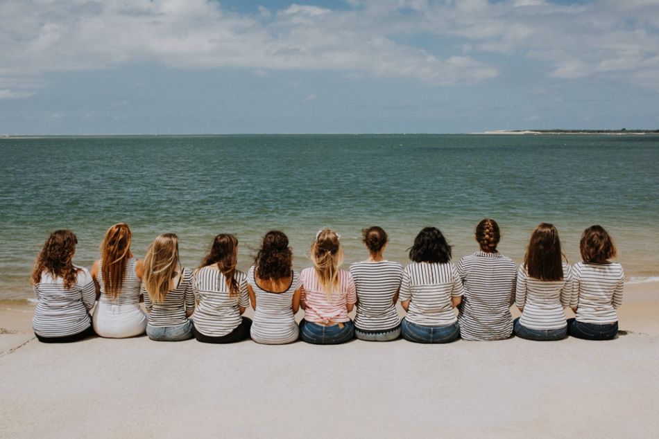 From back, ten bridesmaids and their bride-to-be sitting by the sea in Arcachon in Landes region