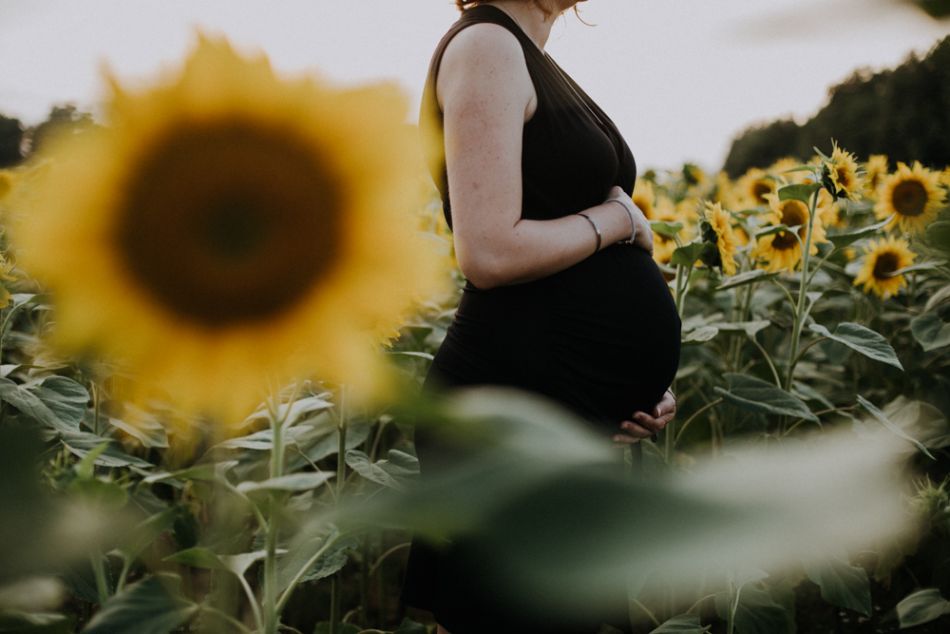 Femme enceinte au milieu des tournesols en séance grossesse