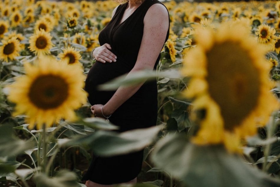 Ventre de femme enceinte et tournesols en séance grossesse à Gimont